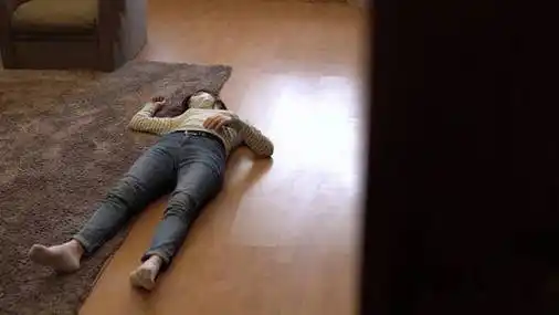 一个戴着医用面罩的女人躺在地板上失去知觉.从门口望去.照片