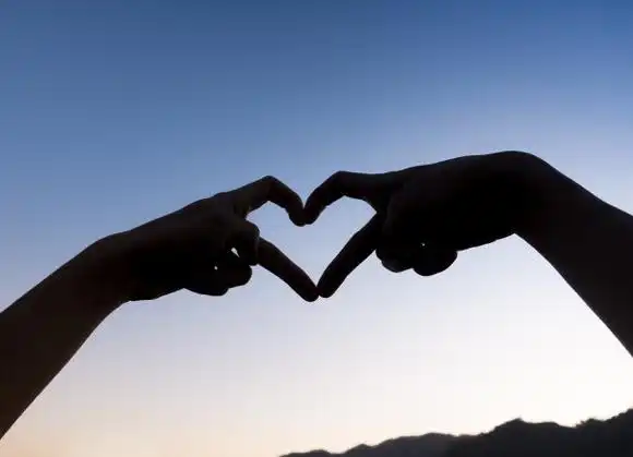 裁剪的手手势心形,对着晴朗的天空.图片