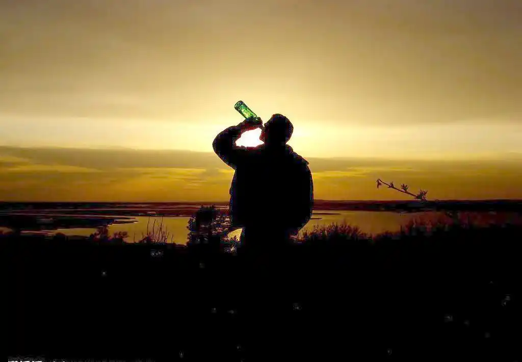 黄昏下海边喝酒的男人图片
