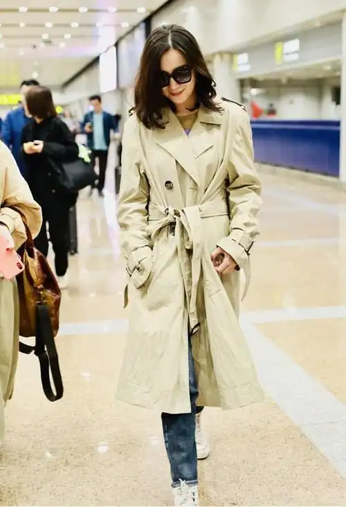 女明星手握暖宝现身机场卡其色系带风衣出行展现出女性的独立