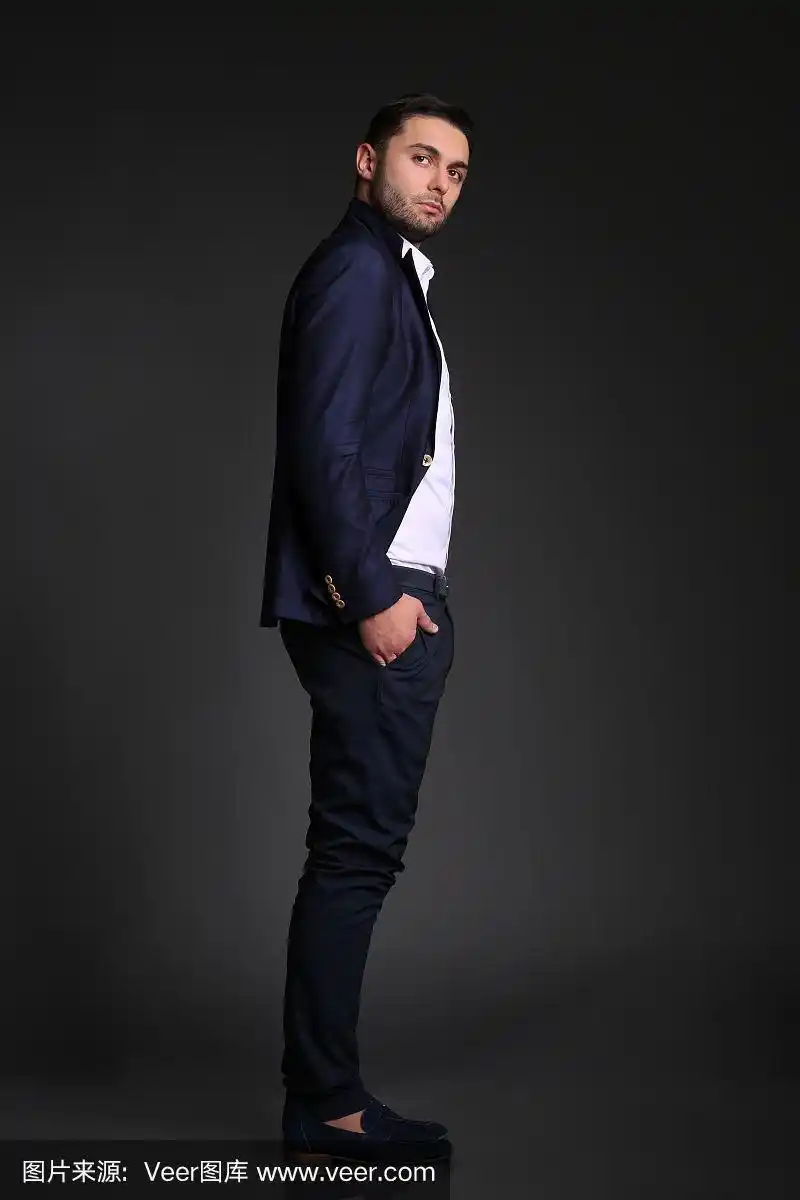 一个穿着黑色西装的帅哥侧身站着看着