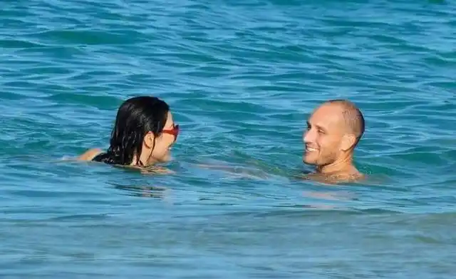 组图:52岁邓文迪与肌肉男海边戏水 穿绿色泳装身材显发福