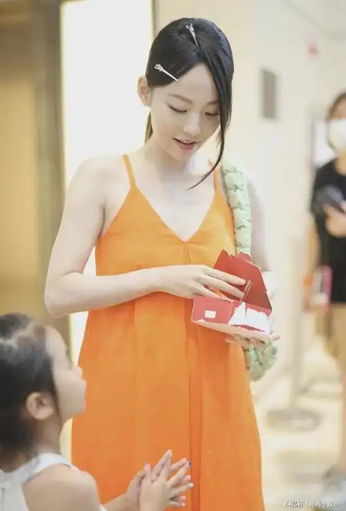 张嘉倪走机场穿橘色吊带裙显肩宽体壮勾栏式溜须刘海太辣眼