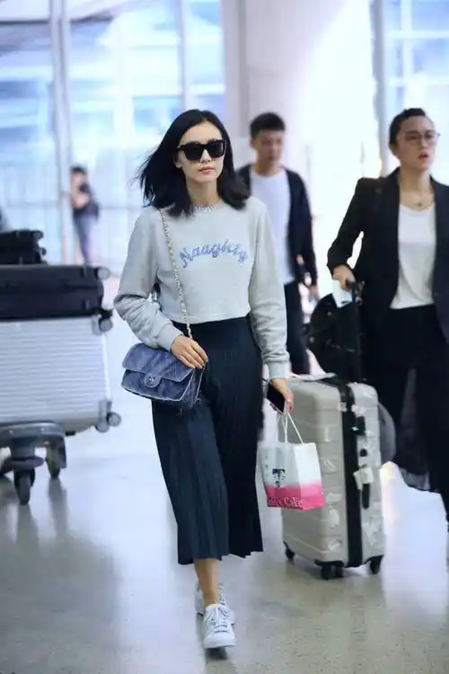 高圆圆走机场妩媚撩发显青春,穿卫衣搭配百褶裙,优雅时尚