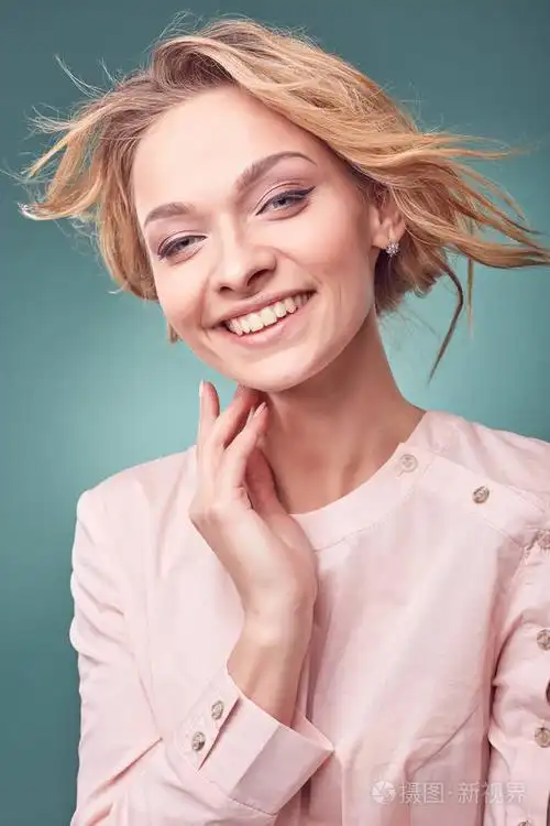 与大眼睛和真诚的微笑,戴在工作室与绿松石背景光粉红色裙子的肖像