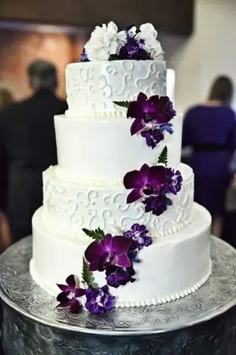 white and purple wedding cake with cascading purple flowers
