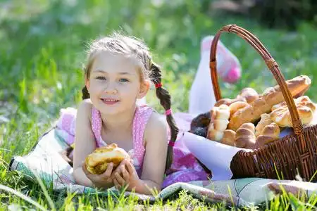 一个孩子在吃面包, 坐在草地上照片