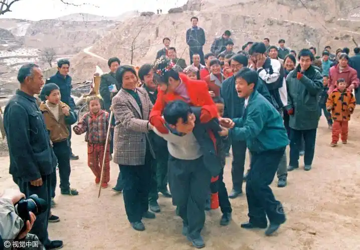 2000年春节,陕北米脂县刘峁村,鞭炮声中新郎在众人的拥簇下背着新娘