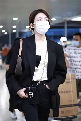 她身穿黑色西装配黑色皮鞋又美又飒. 江疏影边走边甩包.