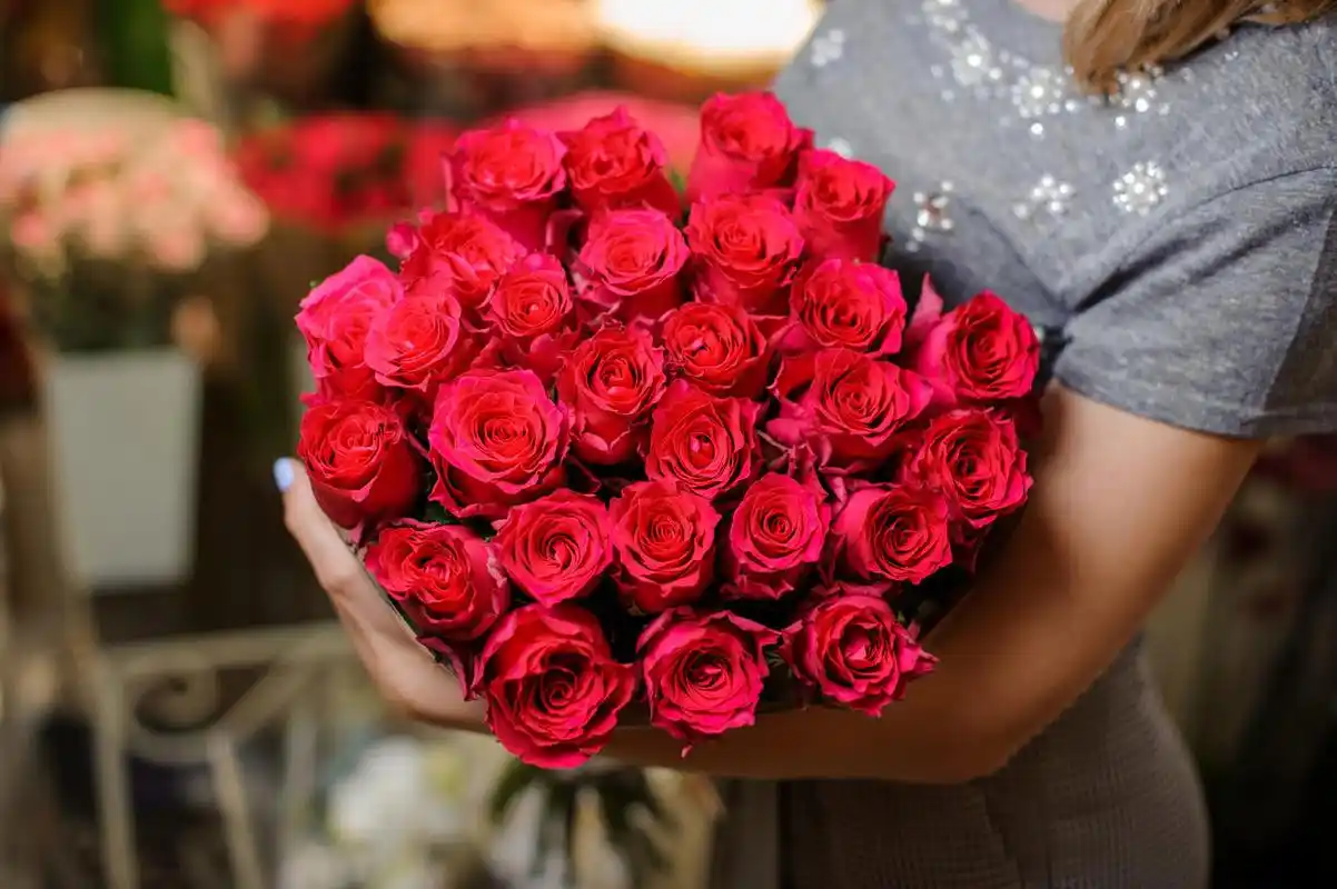 女人穿着灰色的连衣裙,捧着美丽鲜艳的粉红色玫瑰玫瑰鲜花浪漫爱情人