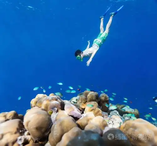 在马尔代夫珊瑚礁浅绿色水下游泳的少年男孩