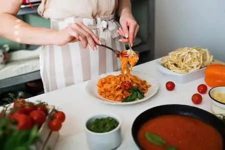 加勒比一锅菜厨房里的年轻女人在家里用平底锅做美味的意大利面和酱汁