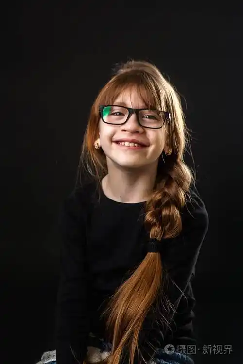 戴眼镜的小女孩笑了笑.黑色背景,大人像.