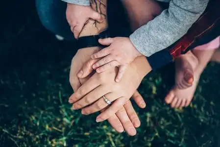 一家人的三只手爸爸妈妈和孩子在绿草上照片