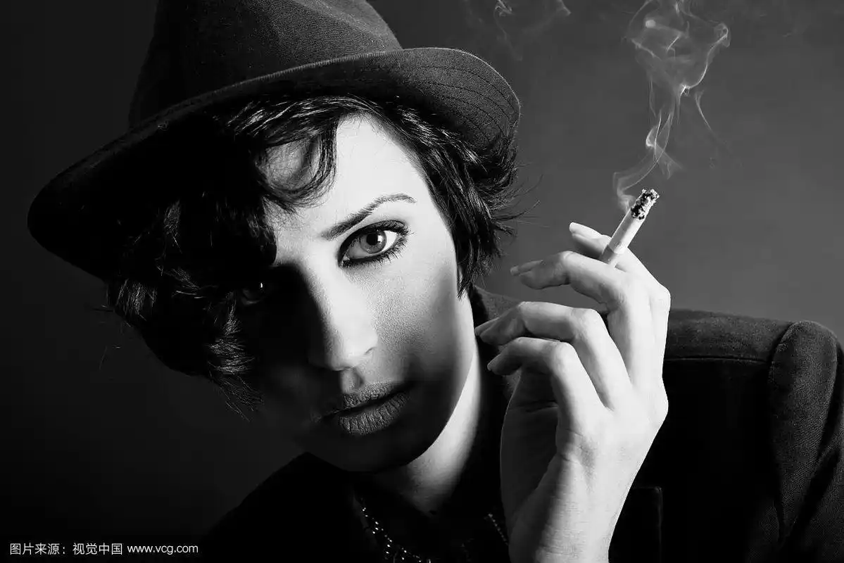 特写肖像的一个黑发女人吸烟的黑色背景戴着一顶帽子