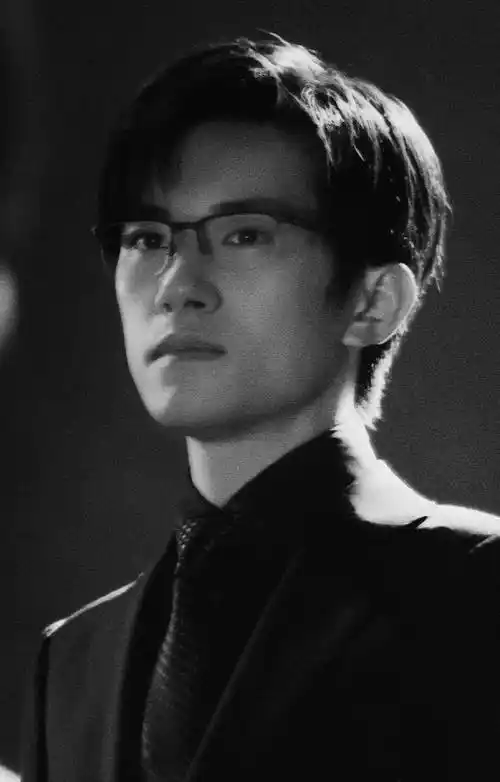 易烊千玺在电影里扮演成功人士的造型,照片里他穿着黑色西装,戴着眼镜