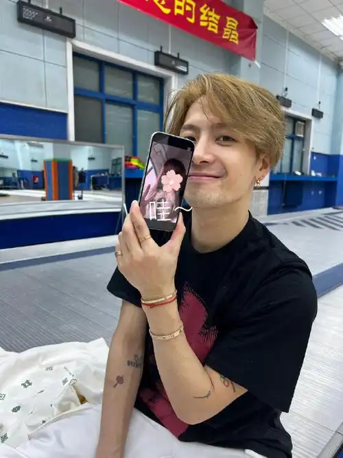 王嘉尔举着粉丝照片合照