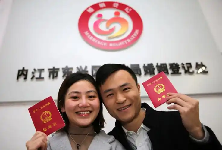 2月14日,在四川省内江市东兴区婚姻登记处,刚领到结婚证的新人李杰(右