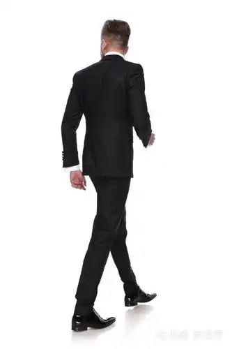 一个穿着燕尾服走路的年轻人的背视图在白色的背景