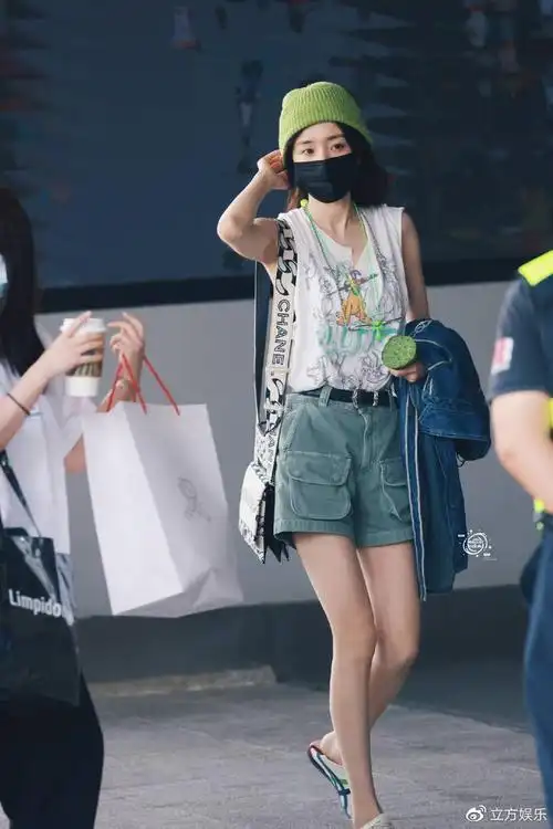 杨幂机场路透戴牛油果绿帽手拿莲蓬穿短裤秀长腿