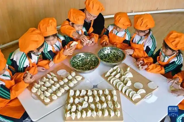 12月20日,山东省枣庄市市中区中兴小学老师(左二)在教学生包饺子.