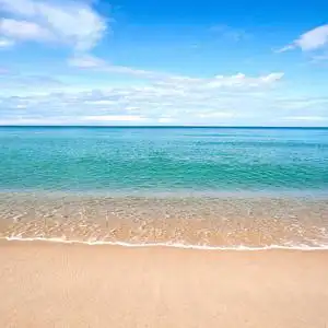 美丽的海滨沙滩与平静水对蓝蓝的天空照片