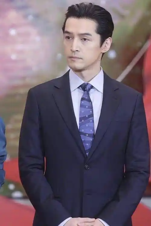 深蓝色的西装套装,搭配蓝色的领带,白色衬衣,尤其是大背头的发型,气场