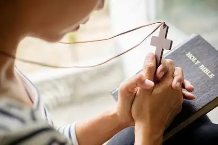 基督教妇女在圣经上祈祷.祈祷时双手交叉,教堂概念中的圣经照片