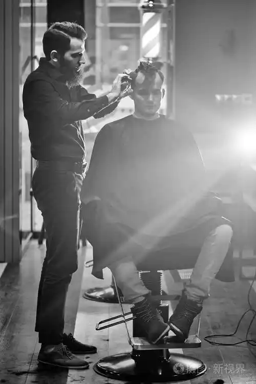 理发店剪客过程中穿黑色衬衫的理发师黑白照片