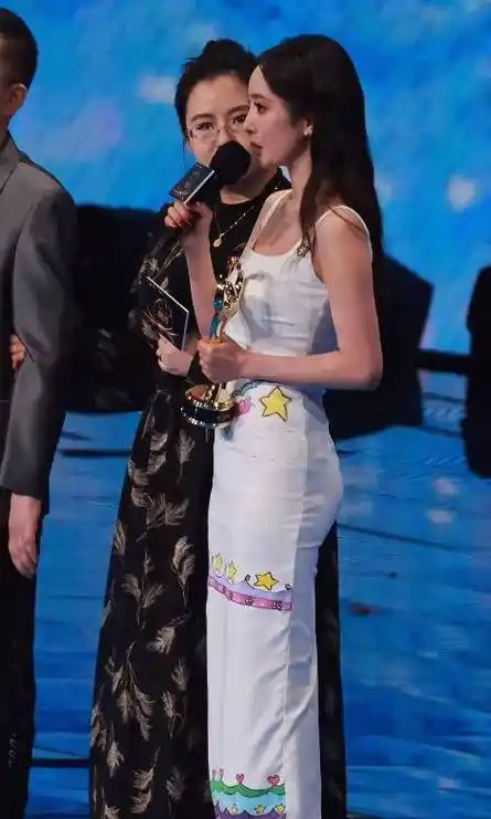 画面中可见白色裙子上面有简单的手绘星星图案,杨幂穿着它上台领奖时