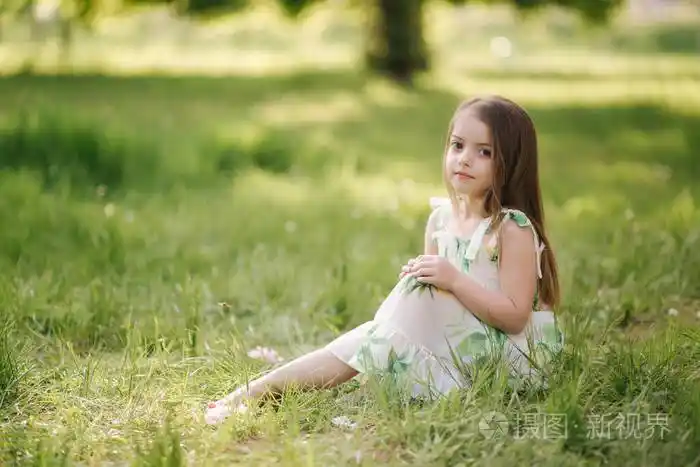 可爱的小女孩赤脚坐在公园的草地上新鲜空气中的快乐孩子检疫结束漂亮