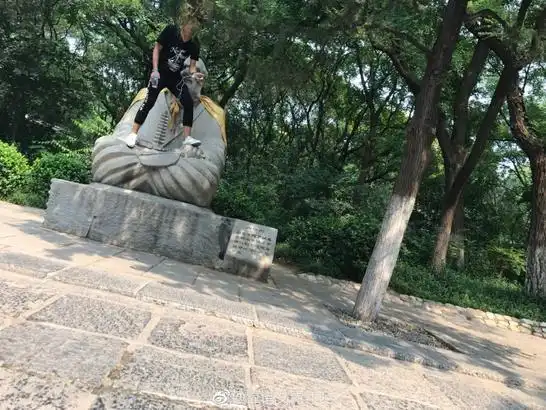 为拍照?男子脚踩千佛山佛像,一脸微笑