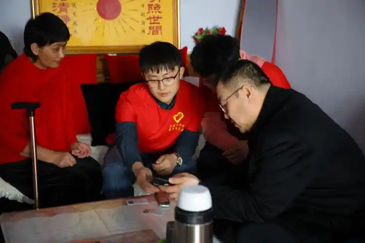 (图为志愿者们帮助老人验证残疾人证)