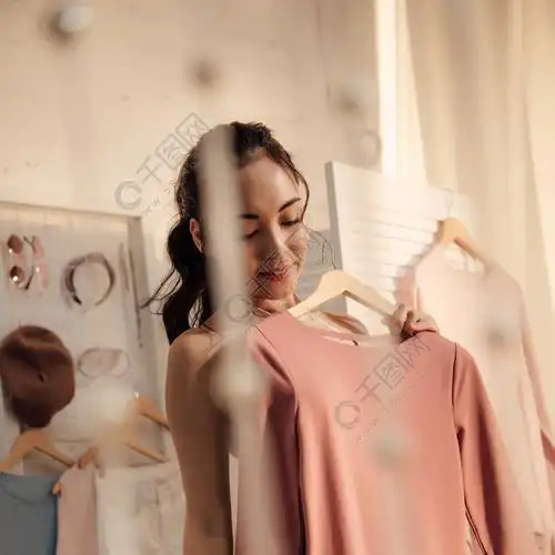 美丽的微笑的亚洲女人在内衣举行衣架与时尚的礼服在衣柜