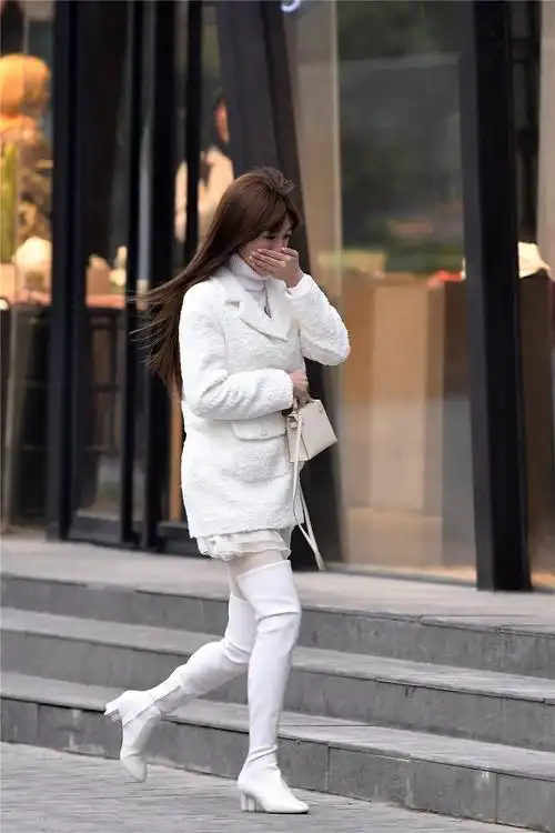 白色粗跟过膝靴搭配白色丝袜毛衣和外套都是白色的