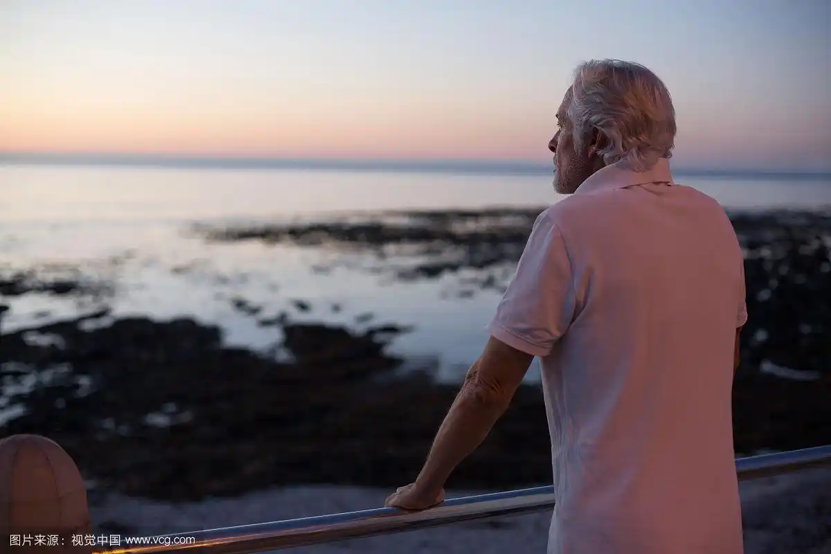 黄昏时分,一位老人站在海滩边