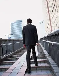城市街道下提箱上街梯的欧美西装男子背影