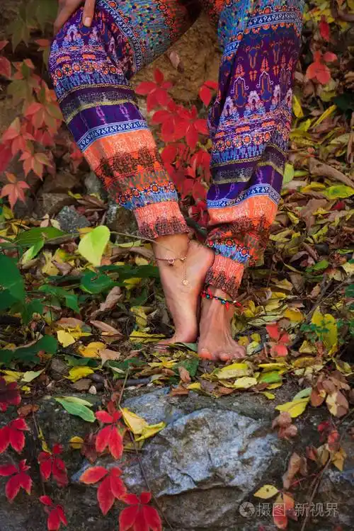 赤脚女子腿在瑜伽姿势彩色秋叶户外日射