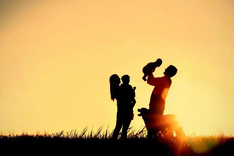 父亲宝贝和孩子和他们的狗在夕阳的天空副本空间或文本的余地一个剪影