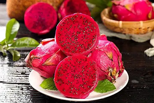 黑底上放着一盘切开的红心火龙果