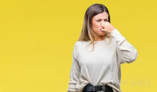 年轻漂亮的女人,随意的白色毛衣,在孤立的背景上,闻到一些臭味和令人