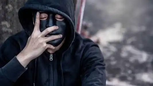 神秘人戴着黑色面具,穿着帽衫,闭上眼睛想着什么.