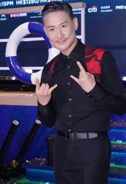 张学友脚踩黑色亮皮皮鞋,还留着酷酷的短发,像个英俊的男模特,而且还