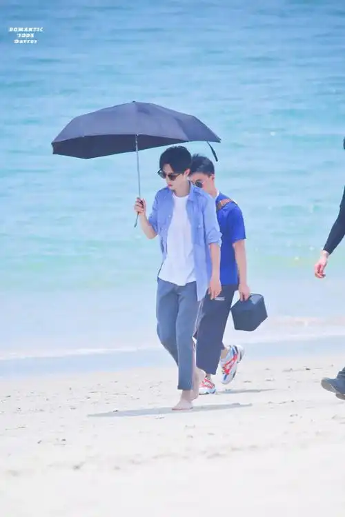 肖战录制《慢游旅行家》的饭拍照片分享,肖战光脚走在海边的沙滩上,如