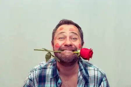 一朵红玫瑰长胡子的成熟男人嘴里衔着一朵红玫瑰.