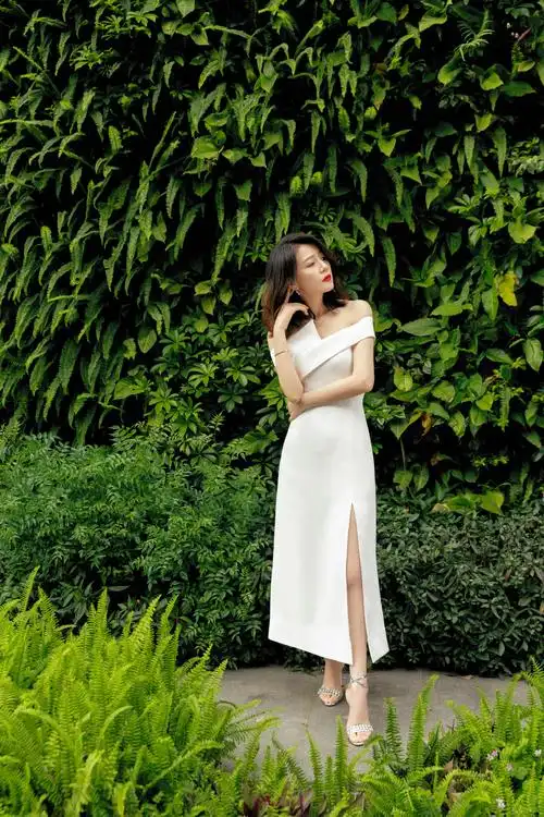 照片中,高圆圆身穿白色一字肩连衣裙,脚蹬银色高跟鞋,留着中长发,莞尔