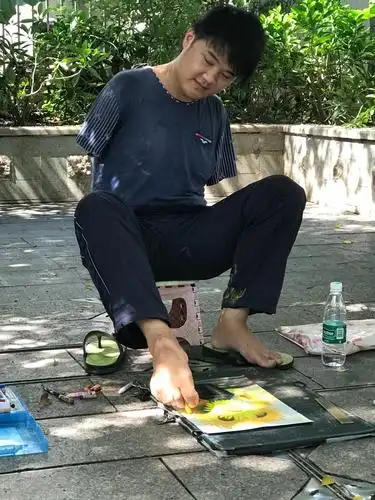 用脚画画的男生,画出了深圳一道美丽的风景线