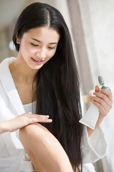 年轻女子给腿部擦护肤品