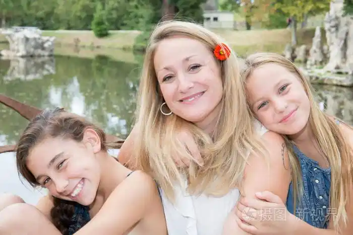 单金发碧眼的母亲与两个女儿户外公园湖
