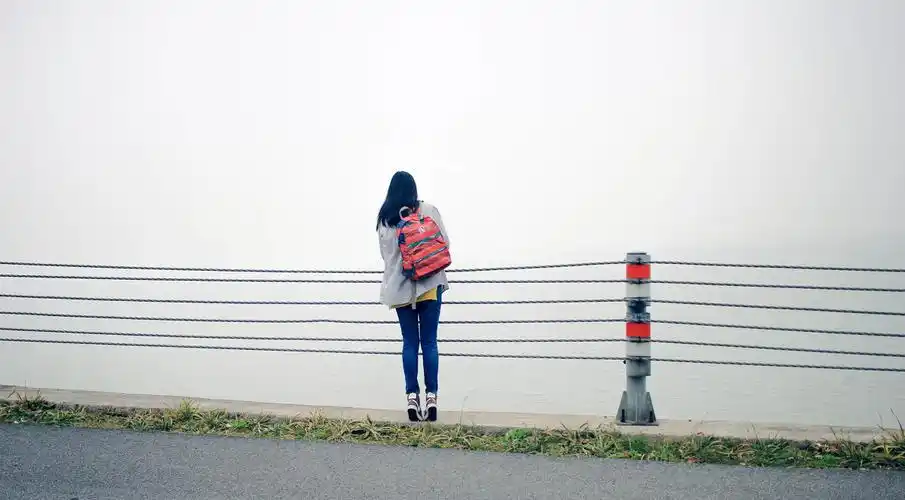 大雨过后,湖面的雾气很深,环湖的盘山公路那边,旅行的姑娘在独自行走.